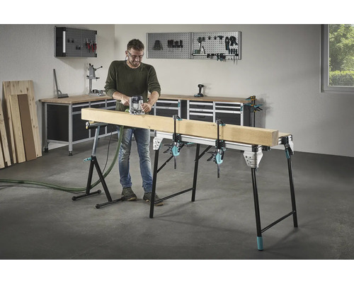 Bărbat frezând lemn pe un banc de lucru cu cleme cu șurub într-un atelier