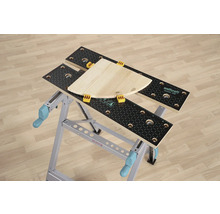 Banc de lucru Wolfcraft Master 200 cu bucată de lemn și cleme de prindere.