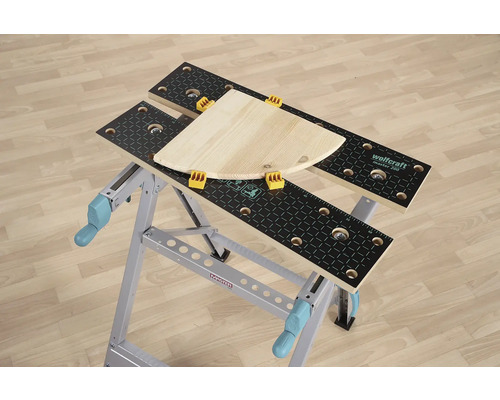 Banc de lucru Wolfcraft Master 200 cu bucată de lemn și cleme de prindere.