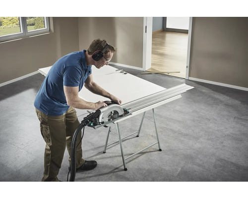 Artizan taie o ușă cu un ferăstrău circular pe un banc de lucru.