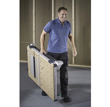 Un bărbat cară o masă de lucru pliată.