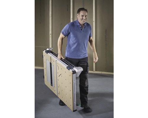 Un bărbat cară o masă de lucru pliată.