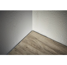 Colțul unei camere cu podea din lemn și perete texturat