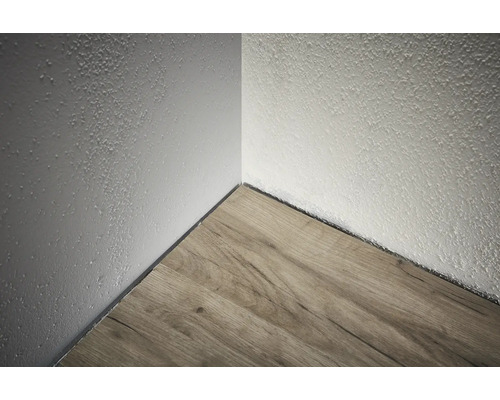 Colțul unei camere cu podea din lemn și perete texturat