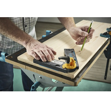 O persoană folosește un șablon de marcare și un creion pe o scândură de lemn.