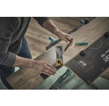 O persoană folosește un banc de lucru, un unghi și un pix pentru a prelucra o bucată de laminat.