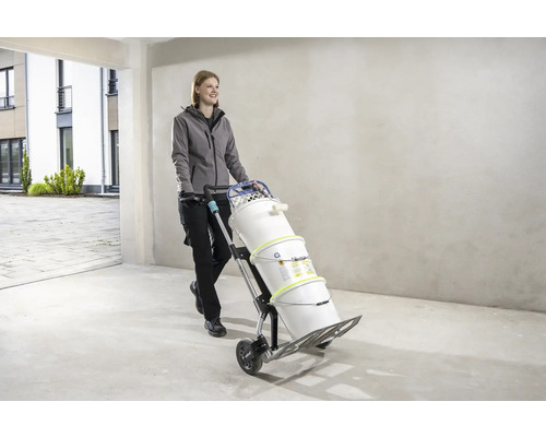 Femeie transportă găleți de vopsea cu un cărucior.