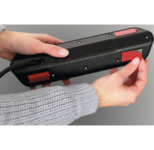 O persoană fixează o bandă prelungitoare cu benzi adezive.