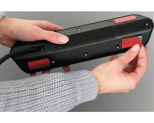 O persoană fixează o bandă prelungitoare cu benzi adezive.