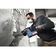 Un bărbat îndepărtează plăcile de faianță cu un ciocan rotopercutor Bosch.