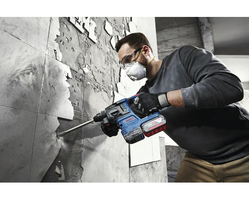 Un bărbat îndepărtează plăcile de faianță cu un ciocan rotopercutor Bosch.
