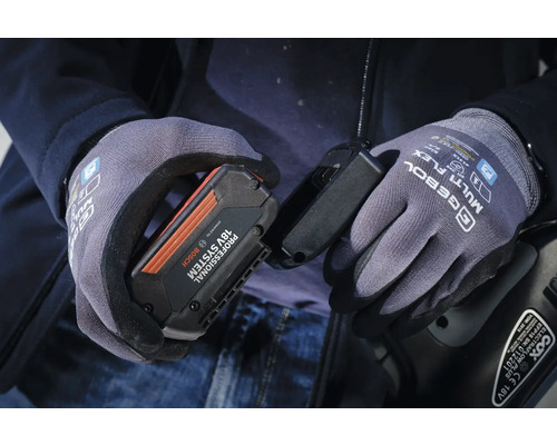 Persoană cu mănuși de lucru ținând bateria Bosch de 18V