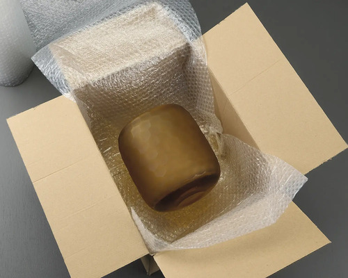 Vază din sticlă maro într-o cutie de carton cu folie cu bule