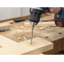 Șurubelniță fără fir înșurubează un șurub într-o scândură de lemn