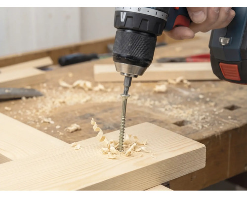 Șurubelniță fără fir înșurubează un șurub într-o scândură de lemn