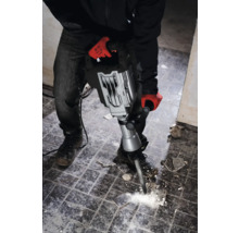 Un bărbat cu mănuși de lucru folosește un ciocan demolator pentru a îndepărta plăcile.