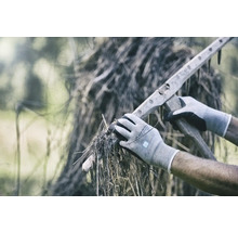 Persoană cu mănuși care adună iarbă uscată cu o greblă de lemn