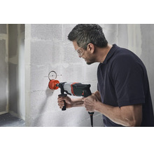 Un bărbat face o gaură într-un zid cu o carotă.