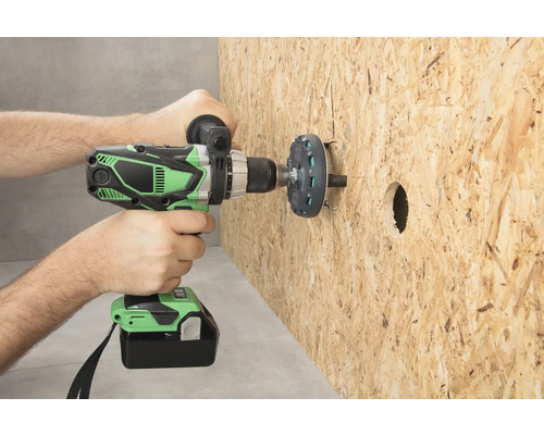 O persoană găurește o placă de lemn cu o șurubelniță cu acumulator.