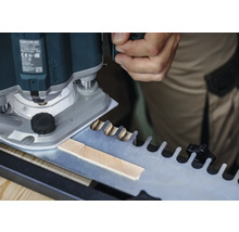 O freză verticală prelucrează o piesă de lucru folosind un șablon pentru îmbinări în coadă de rândunică.