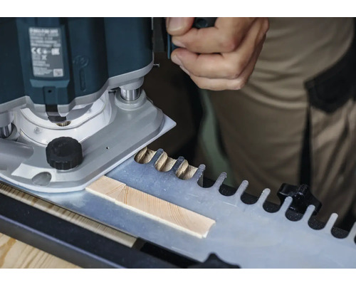 O freză verticală prelucrează o piesă de lucru folosind un șablon pentru îmbinări în coadă de rândunică.