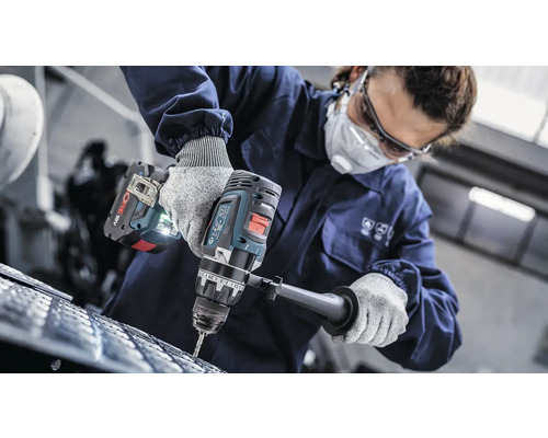 O persoană găurește un material cu o mașină de găurit fără fir.