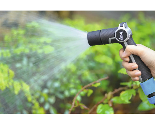 O mână ține un pistol de stropit grădina și udă plantele.