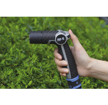 Pulverizator de grădină în mână în fața arbuștilor