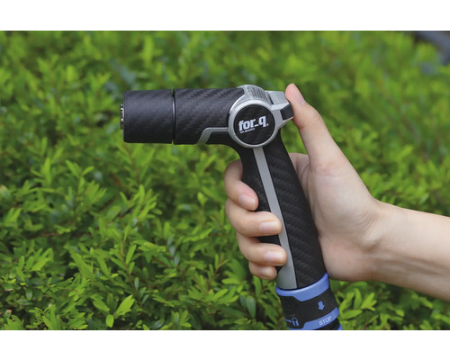 Pulverizator de grădină în mână în fața arbuștilor