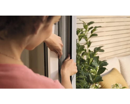 Femeie care fixează o plasă de insecte pe o fereastră.