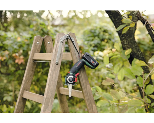 Fierăstrău de grădină cu acumulator pe o scară de lemn în grădină