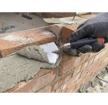 Zidar așează cărămida cu o mistrie pe un șantier