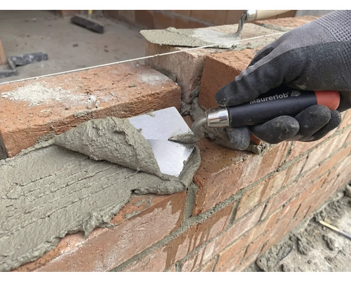 Zidar așează cărămida cu o mistrie pe un șantier