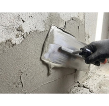 O persoană nivelează tencuiala cu o gletieră pe un perete.