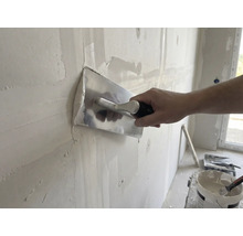 Artizan finisează peretele cu gletieră și tencuială