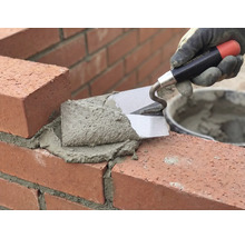 Zidar zidește cărămizi cu mistria și mortar.