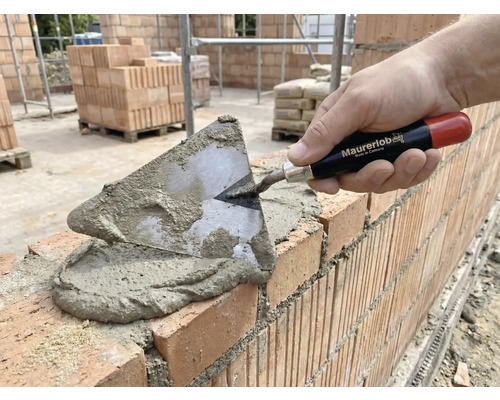 Zidar care pune cărămizi cu o mistrie și mortar.