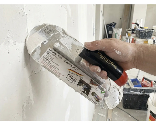 Gletieră Superglatt cu mâner în mână la tencuirea unui perete