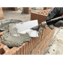 Zidar cu mistria aplicând mortar pe cărămizi pentru zidărie