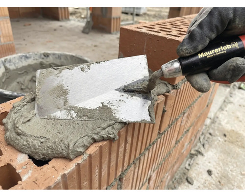 Zidar cu mistria aplicând mortar pe cărămizi pentru zidărie