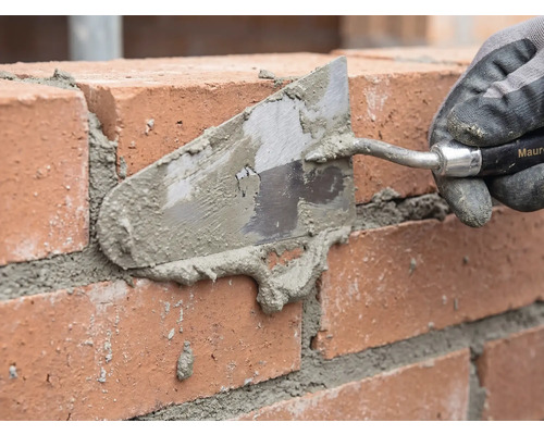 Zidar care chituieste un zid de caramida cu o mistrie