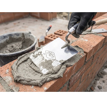 Zidar la lucru cu mistrie, mortar și cărămizi