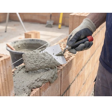 Zidar care aplică mortar și cărămizi pentru construcția unui zid