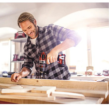 Un bărbat găurește o scândură de lemn cu o șurubelniță electrică cu acumulator.