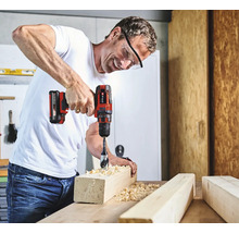 Un bărbat găurește o bucată de lemn cu o șurubelniță electrică