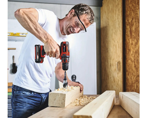 Un bărbat găurește o bucată de lemn cu o șurubelniță electrică