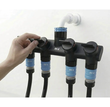 Distribuitor furtun de grădină cu patru conexiuni și o mână care acționează unul dintre robinete