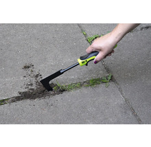 O mână folosește o racletă pentru rosturi pentru a îndepărta buruienile dintre pietrele de pavaj.