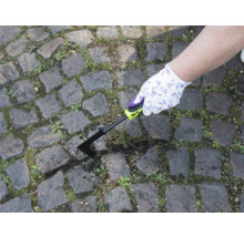 O persoană îndepărtează buruienile cu o racletă de rosturi de pe o potecă pavată.