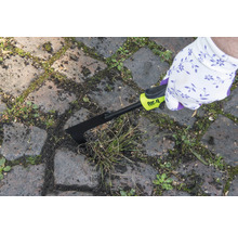 O persoană îndepărtează buruienile dintre pietrele de pavaj cu o racletă pentru rosturi for_q.